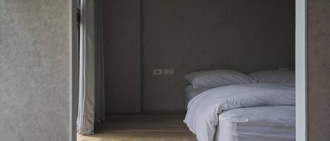A bedroom with a bed, a window, and a door.