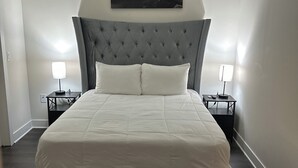 A modern bedroom with a large bed, a ceiling fan, and a painting of a waterfall. - Luxurious Condo Midtown Atlanta (Atlanta)