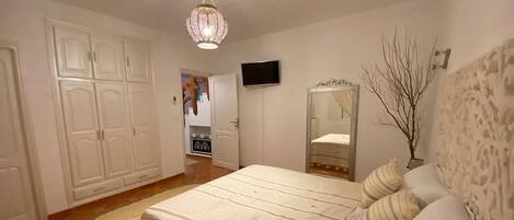 Un dormitorio con cama, televisión, armario y espejo.