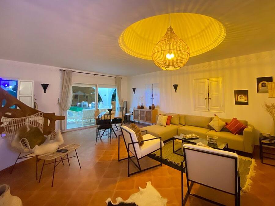 A living room with a sofa, chairs, a coffee table, and a large yellow hanging light fixture.