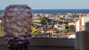 Vista de uma cidade costeira vista da janela, com um vaso decorativo em primeiro plano.