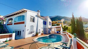 Uma villa com piscina, área de estar externa e vista para a paisagem ao redor.