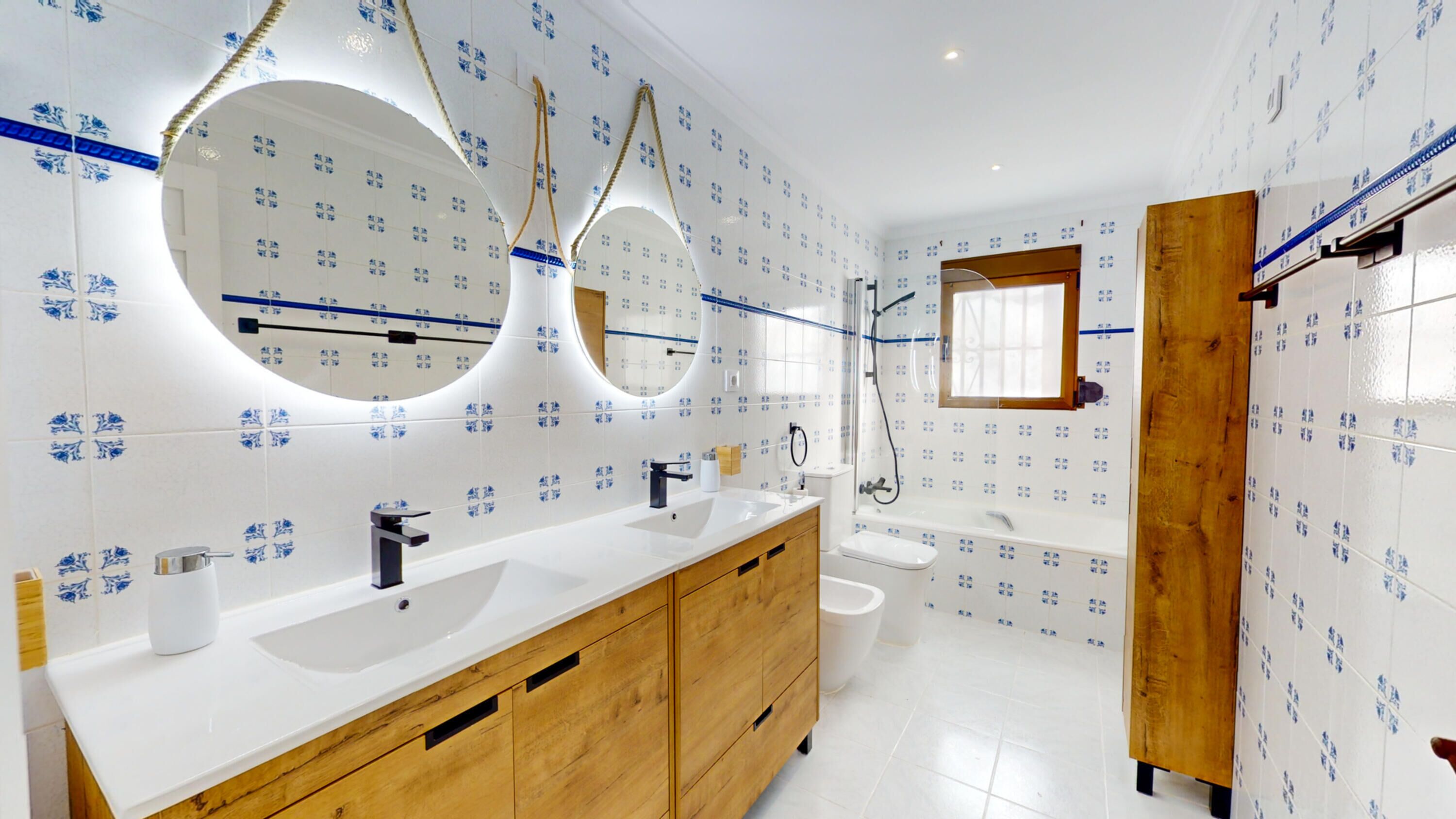 A modern bathroom with two sinks, wooden cabinets, and a large mirror.