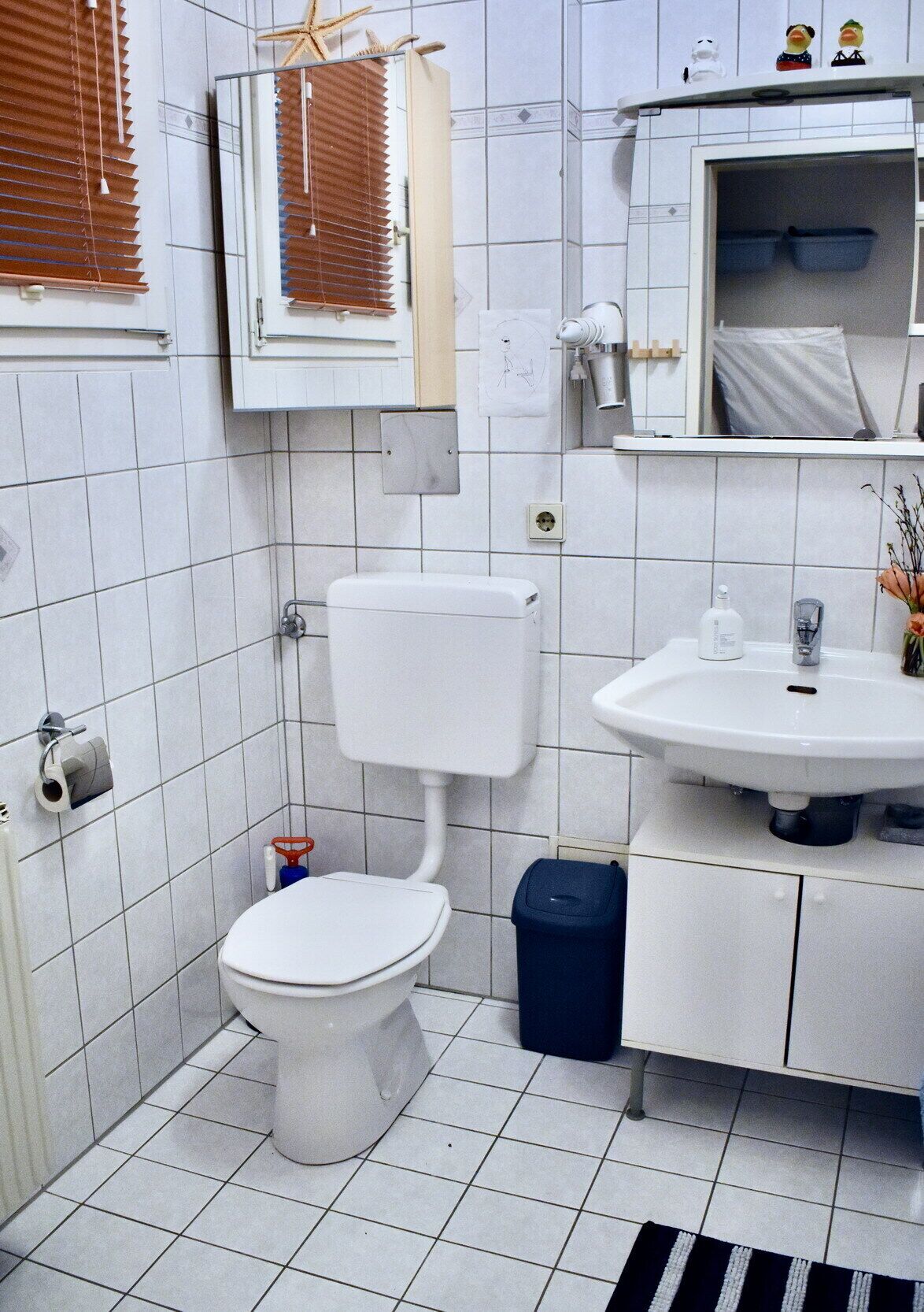 Une petite salle de bain propre, équipée de toilettes, d’un lavabo et d’un miroir.