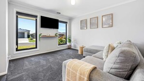 A modern living room with a grey sofa, a flat-screen TV, and large windows. - Spacious Living, Lucas (Lucas)