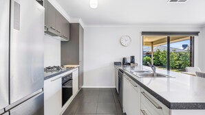 A modern kitchen with a gas stove, oven, dishwasher, and a large window with a view of greenery. - Spacious Living, Lucas (Lucas)