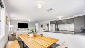 A modern kitchen with a wooden dining table, grey cabinets, and a built-in stove. - Spacious Living, Lucas (Lucas)