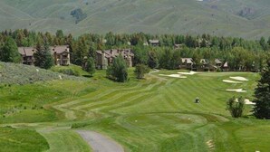 A golf course with a path leading to a building complex surrounded by trees and hills. - Elkhorn Ridge Condo + FREE Resort Amenities (Sun Valley)