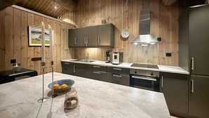 A modern kitchen with wooden paneling, stainless steel appliances, and a marble countertop. - Awesome home in Hornindal with WiFi (Hornindal)