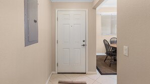 Un couloir avec une porte blanche, un interrupteur et un coin repas comprenant des chaises et une table.