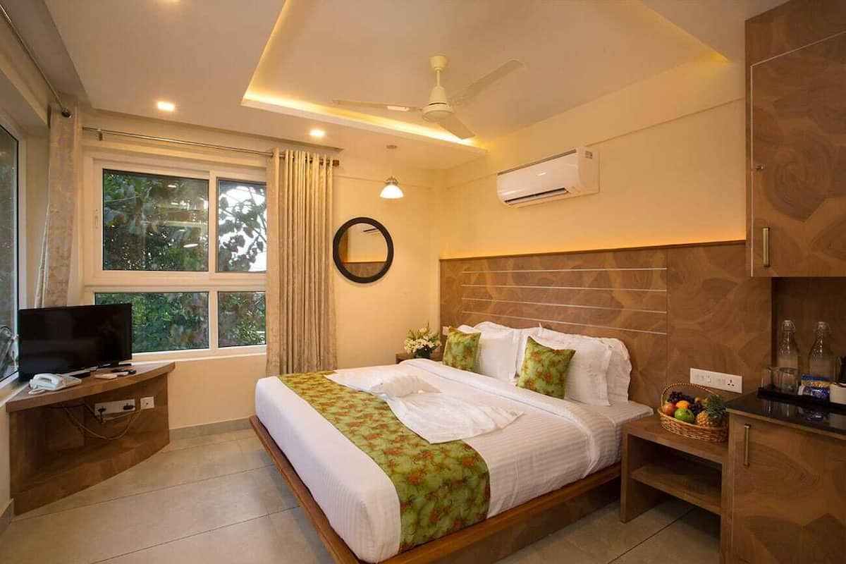 Una habitación de hotel con cama, televisión, escritorio y ventana con cortinas.