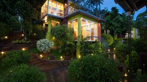 Une maison à deux étages dotée d ’un balcon, entourée d’une végétation luxuriante et d’un jardin bien éclairé.