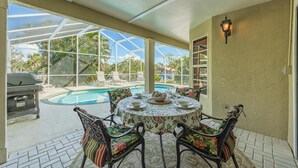 A covered patio with a pool, outdoor seating, and a grill. - Newly Renovated, Gulf Access & Heated Pool - Villa Following the Sun - Roelens Vacations (Cape Coral)