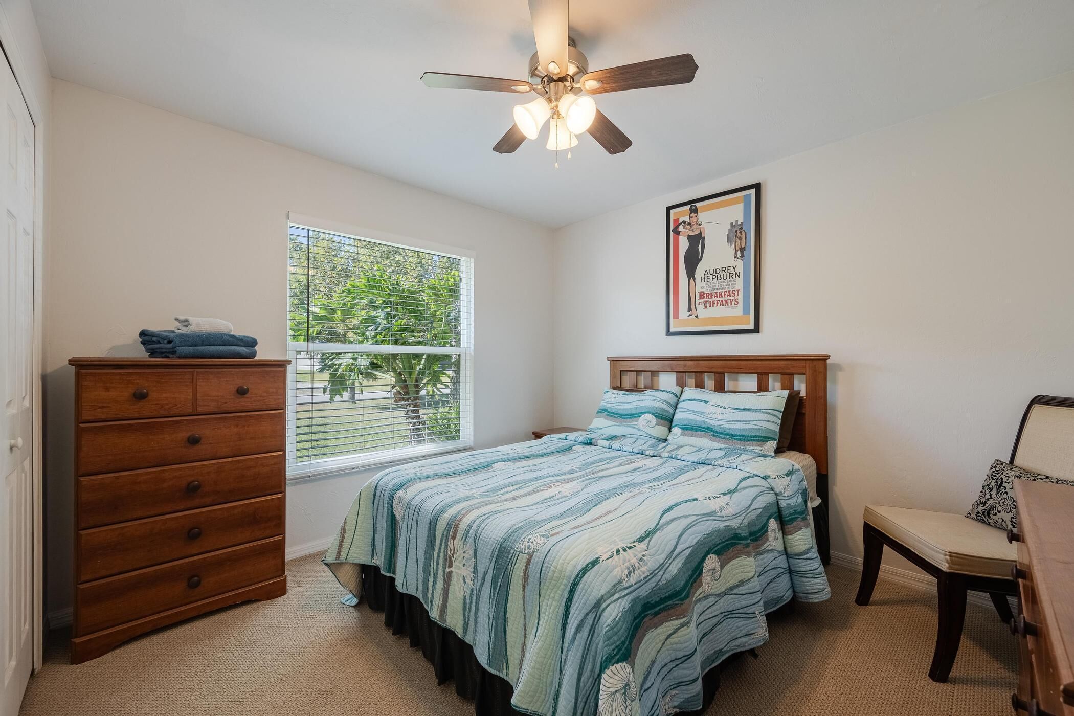 A bedroom with a bed, dresser, and ceiling fan.