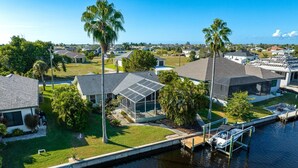 A residential area with houses, a dock, and a body of water. - Newly Renovated, Gulf Access & Heated Pool - Villa Following the Sun - Roelens Vacations (Cape Coral)