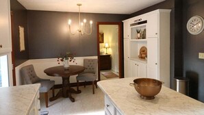 A dining area with a round table, chairs, a chandelier, a white cabinet with shelves, and a clock on the wall. - Spacious Family Home w/ Fireplace & Fire Pit (Grayson)