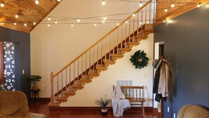 A staircase with wooden railings, a potted plant, a bench, and a coat rack. - Spacious Family Home w/ Fireplace & Fire Pit (Grayson)