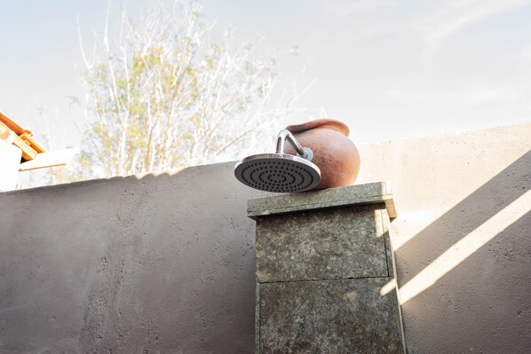 A showerhead mounted on a stone structure with a concrete wall in the background.