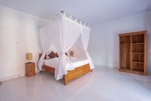 A bedroom with a four-poster bed, a wooden nightstand, a bedside table, and a wardrobe. - Garvi Villa (Karangasem)