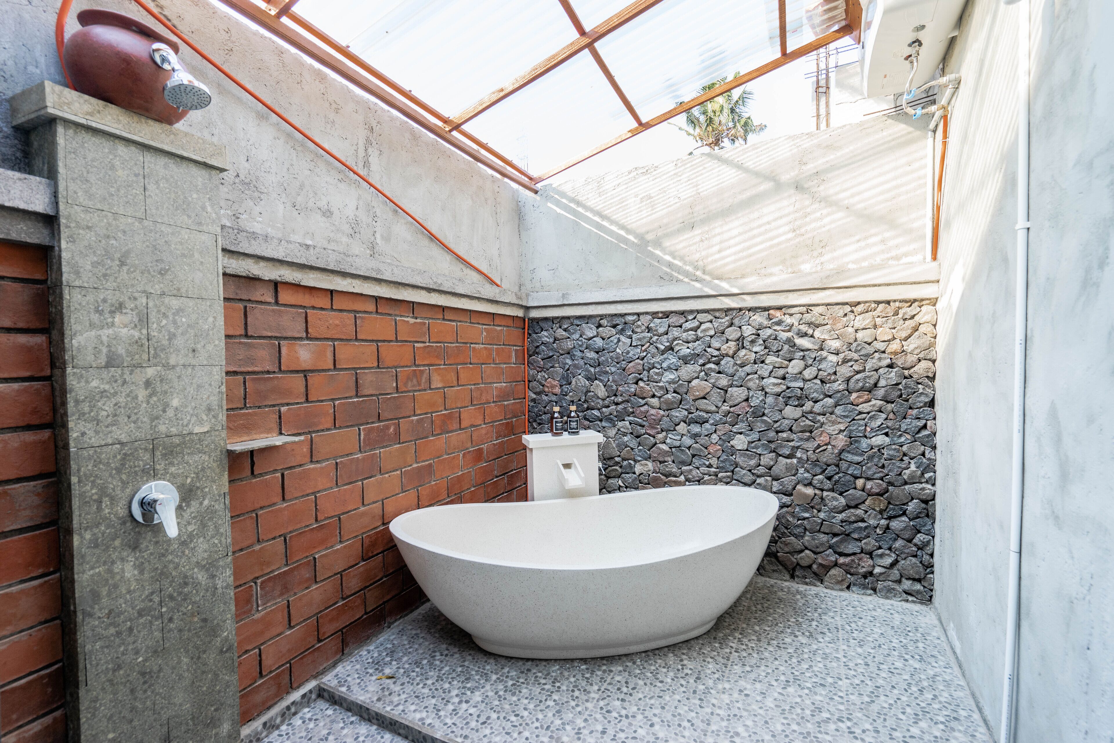 Un baño moderno con una bañera independiente, una pared de ladrillo y una pared de piedra.