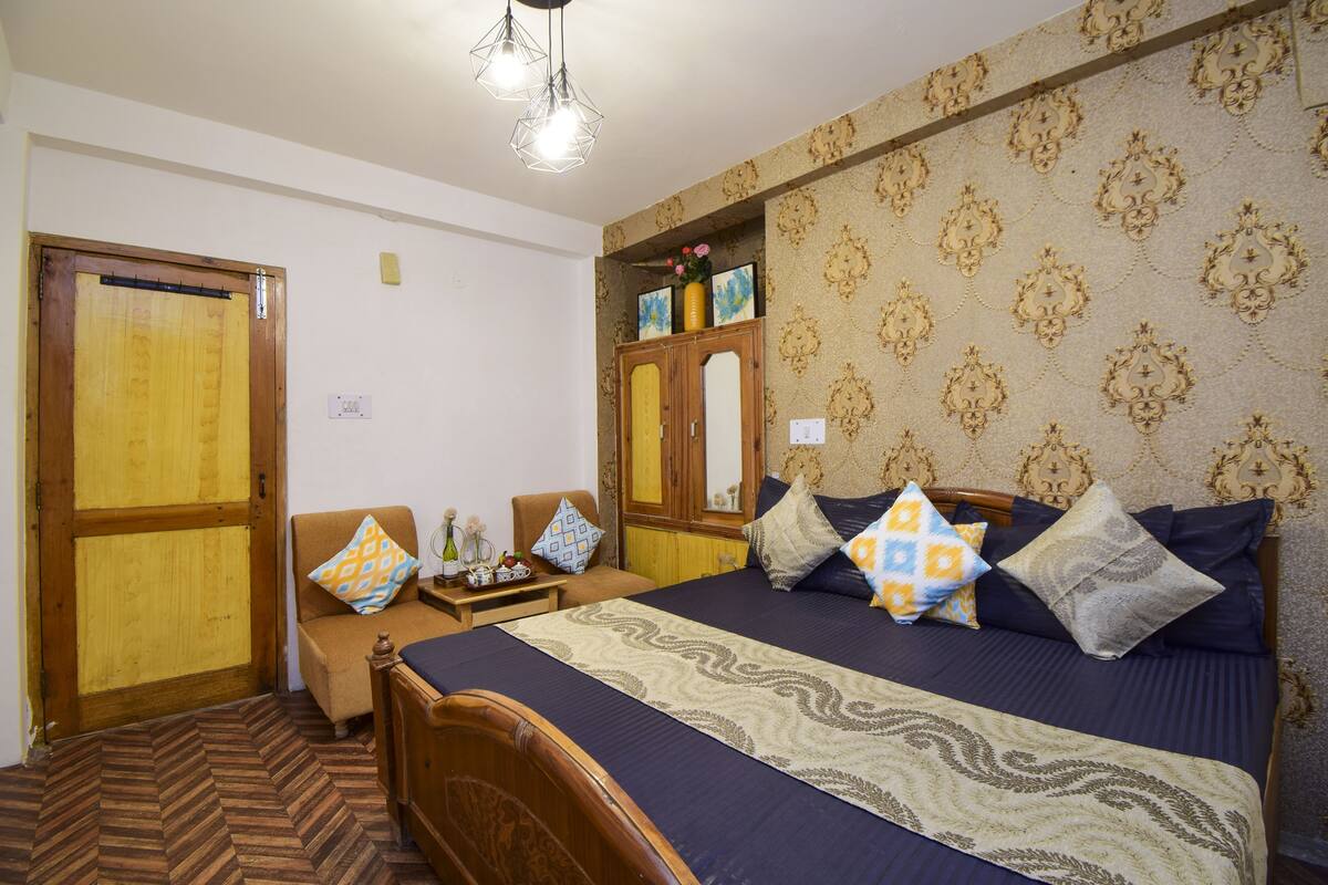 Un dormitorio con cama, cabecero de madera, papel tapiz estampado y suelo con dibujo de espiga.