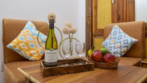 Una mesa de madera con una botella de vino, dos copas y una cesta de fruta.