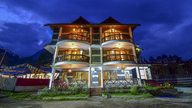 Un hotel de varios pisos con balcones, una escalera y vistas a las montañas.