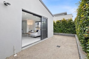 Une maison moderne dotée d’une porte-fenêtre coulissante qui donne sur un espace de vie comprenant un canapé et une table basse.