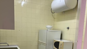 A compact kitchen with a sink, a refrigerator, a microwave, and a white cabinet. - Apartamento Canaleta (Punta Umbría)