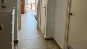 A hallway with a tiled floor leading to a balcony with a view. - Apartamento Canaleta (Punta Umbría)
