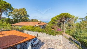 Una villa con techo de tejas, patio de piedra y vista al mar.
