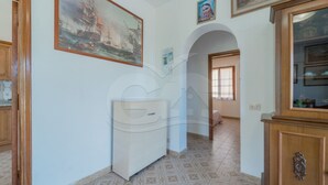 Un pasillo con suelo de baldosas, un armario de madera y un cuadro en la pared.