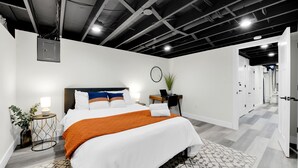 Une chambre d’hôtel moderne avec un grand lit, des tables de chevet, un bureau et une plante en pot.