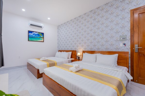 A hotel room with two beds, a painting, an air conditioner, and a wooden door.