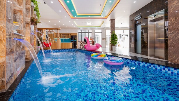 An indoor swimming pool with clear water, a pink flamingo float, and a ceiling with recessed lighting. - 126 Vung Tau Pool Villa Back Beach (Ho Chi Minh City)