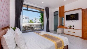 A modern hotel room with a large bed, a TV, and a balcony with a view of buildings. - 126 Vung Tau Pool Villa Back Beach (Ho Chi Minh City)