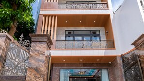 A modern hotel entrance with a marble facade, a balcony with decorative railings, and a sign indicating the address. - 126 Vung Tau Pool Villa Back Beach (Ho Chi Minh City)
