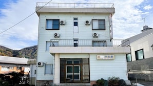 Un edificio de dos pisos con techo plano, varias unidades de aire acondicionado y una entrada visible con puerta de vidrio.