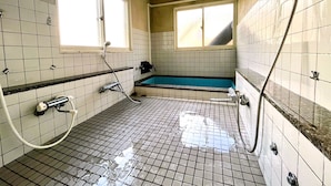 Un baño pequeño con azulejos, una bañera, una ducha y una ventana que deja entrar luz natural.