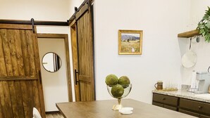 A kitchen with a wooden island, bar stools, a sliding barn door, a framed landscape painting, and a coffee maker. - A clean, comfortable space just off the interstate with easy parking. (Worden)
