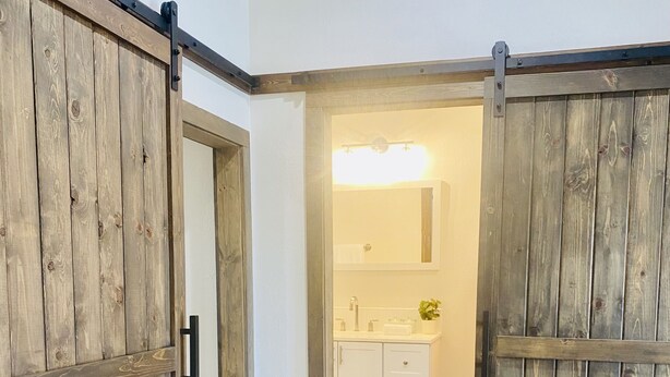 A hallway with wooden sliding doors leading to a bathroom. - A clean, comfortable space just off the interstate with easy parking. (Worden)