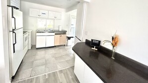 A modern kitchen with white cabinets, a black countertop, and a sign that reads "Welcome with Password." - Aubin Paradise (Windsor)