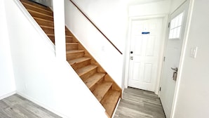 A staircase leading to a landing with a white door, wooden steps, and a grey floor. - Aubin Paradise (Windsor)