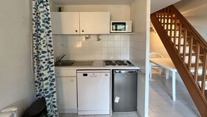 A compact kitchen with white cabinets, a microwave, a sink, a stove, and a dishwasher.