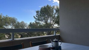 A balcony with a table set for tea, featuring a tray with cups, a teapot, and a sugar bowl.