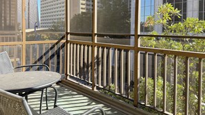 Een balkon met een tafel en stoelen, met uitzicht op een stadsgezicht met hoge gebouwen.