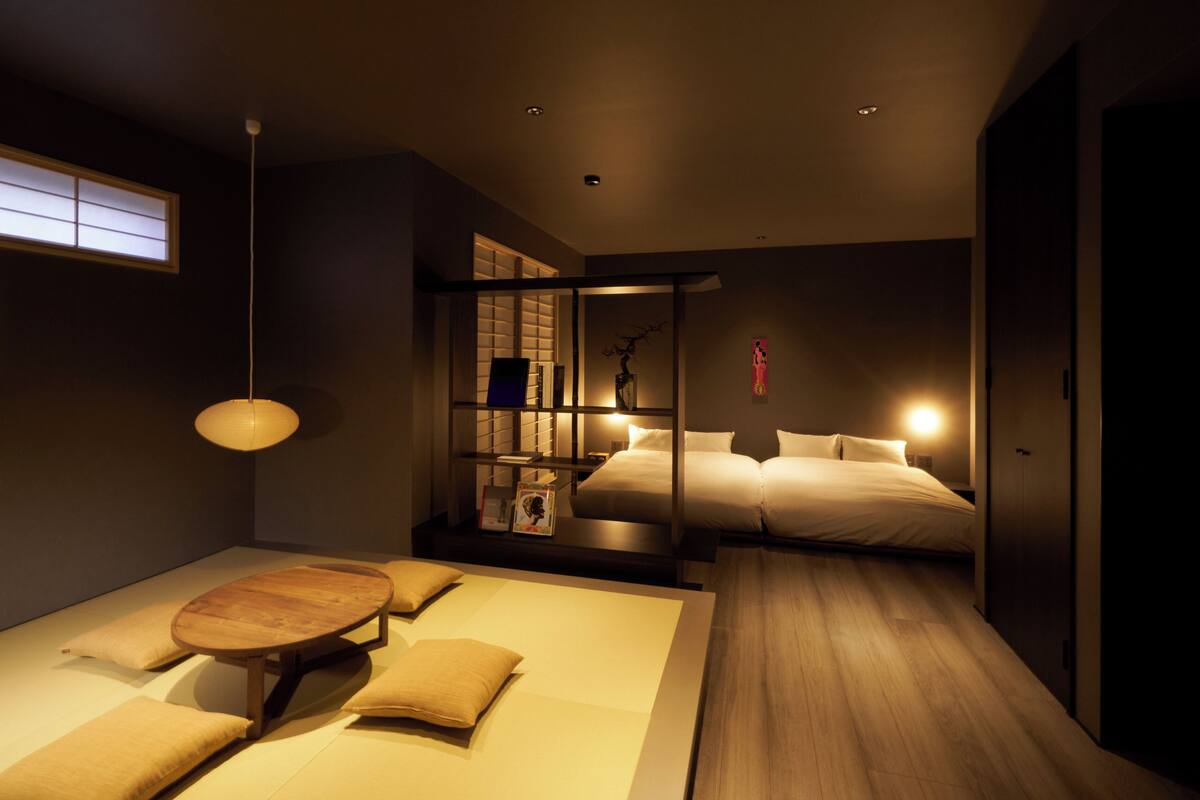 Un dormitorio moderno con una cama, mesitas de noche, suelo de madera y una ventana con persianas.