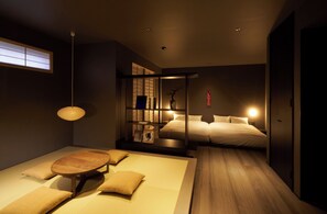 A modern bedroom with a bed, bedside tables, a wooden floor, and a window with blinds. - YANAKA SOW (Tokyo)
