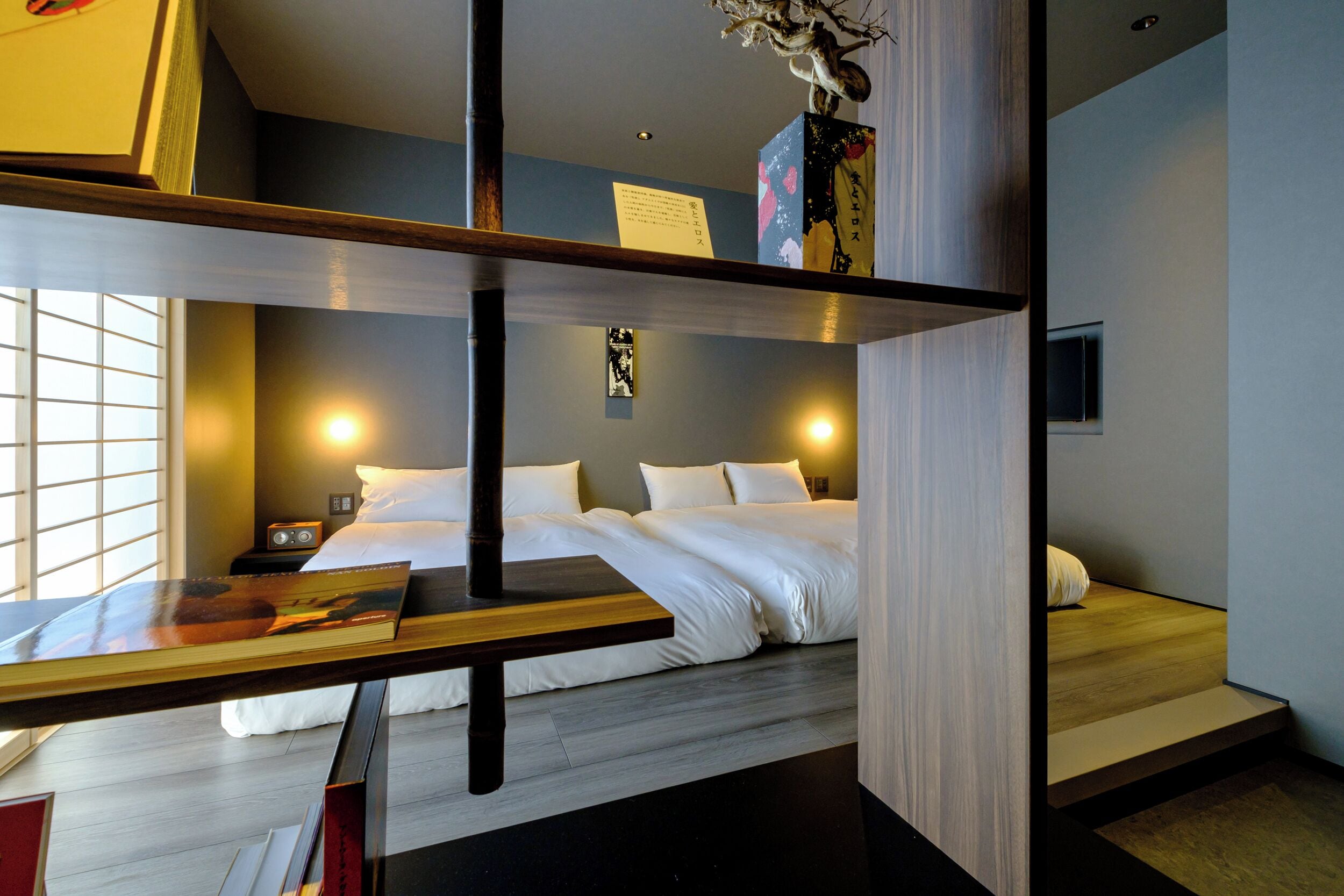 A modern hotel room with a bed, bedside table, and a view of the city.