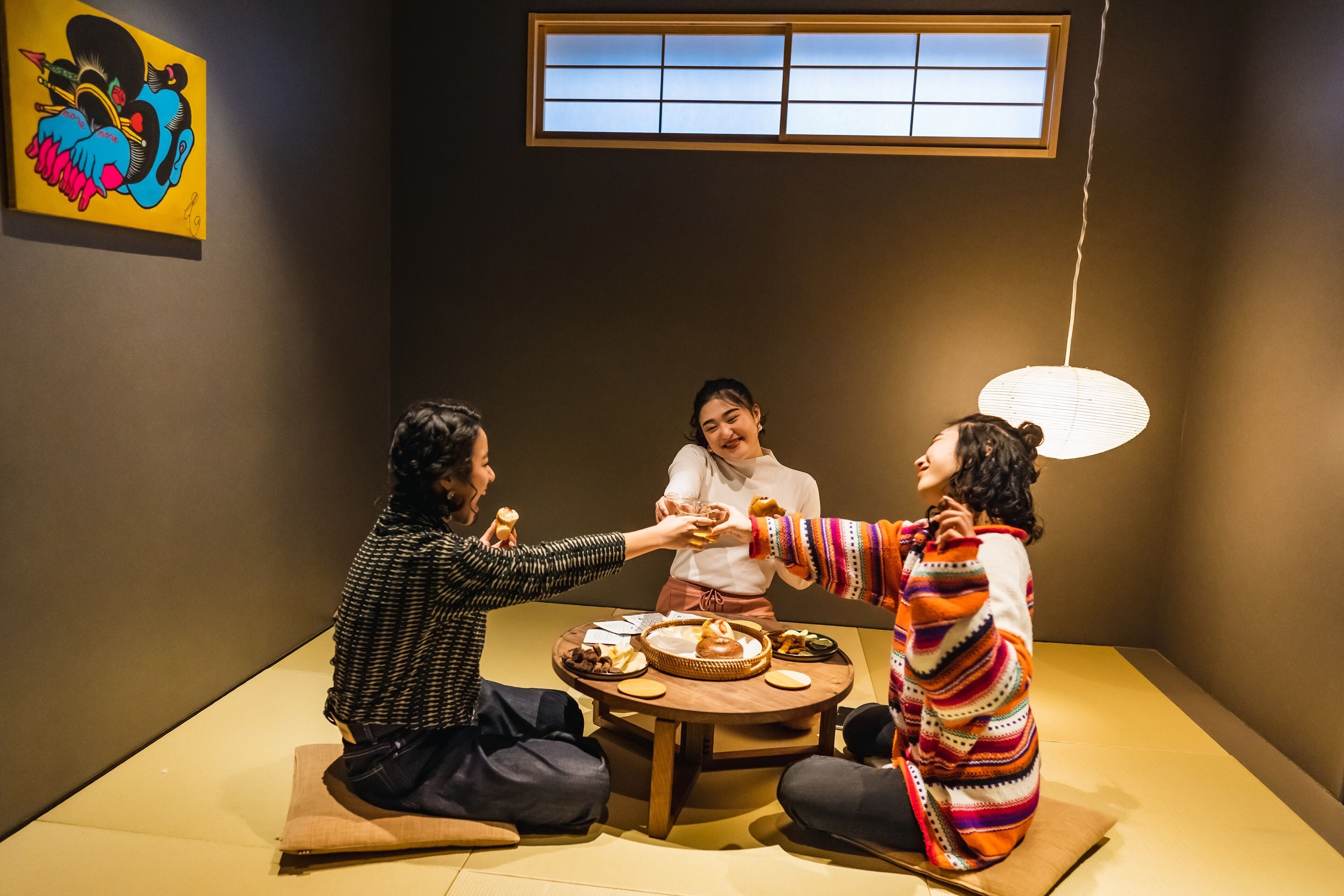 Una habitación con esteras de tatami, una mesa baja con comida y una ventana tradicional japonesa.